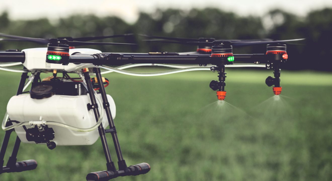 Closeup view of agriculture drone spraying water fertilizer on the green field. Drones spraying pesticides to grow potatoes.